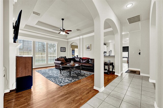 7419 Place Vendome, Spring, TX 77379 - living area with a ceiling fan, light wood finished floors, a tray ceiling, baseboards, and arched walkways
