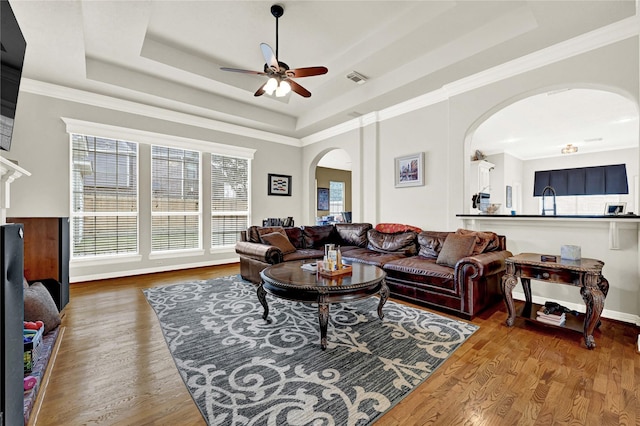 7419 Place Vendome, Spring, TX 77379 - living area featuring arched walkways, a tray ceiling, a ceiling fan, wood finished floors, and baseboards