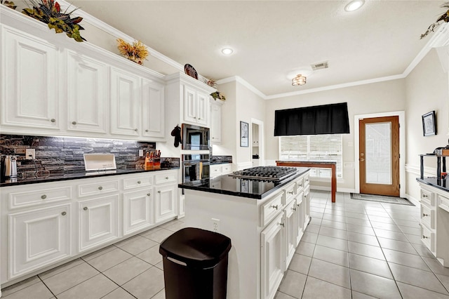 7419 Place Vendome, Spring, TX 77379 - kitchen featuring stainless steel appliances, a center island, light tile patterned flooring, ornamental molding, and dark countertops