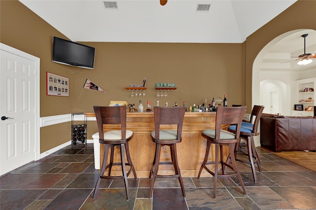 7419 Place Vendome, Spring, TX 77379 - indoor dry bar featuring arched walkways, lofted ceiling, stone tile flooring, ceiling fan, and baseboards
