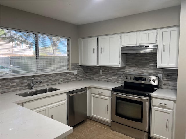 kitchen featuring under cabinet range hood, light countertops, decorative backsplash, stainless steel appliances, and a sink