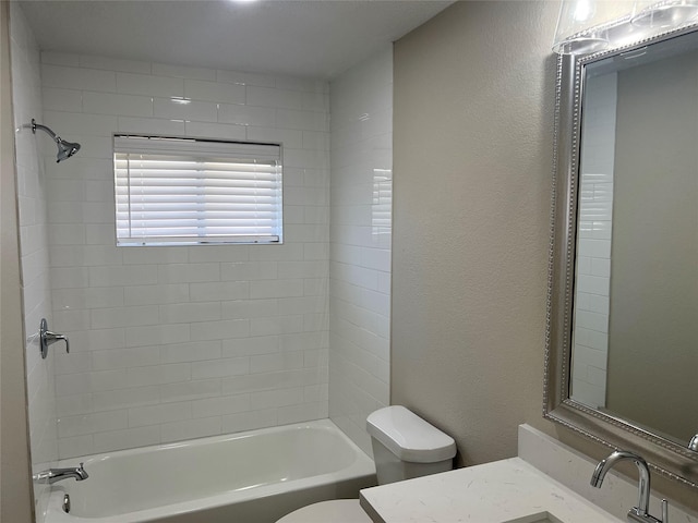 bathroom with vanity, toilet, washtub / shower combination, and a textured wall