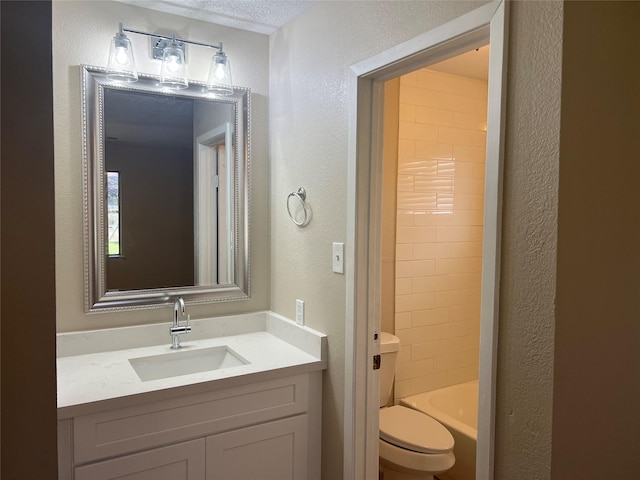 bathroom featuring toilet, vanity, and a textured wall