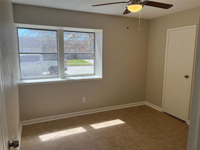 tiled spare room with baseboards, a textured ceiling, and a ceiling fan