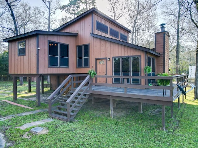 rear view of property featuring a wooden deck, stairway, a lawn, and a chimney