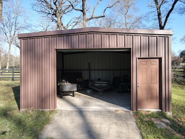 view of outbuilding with driveway, an outdoor structure, and fence