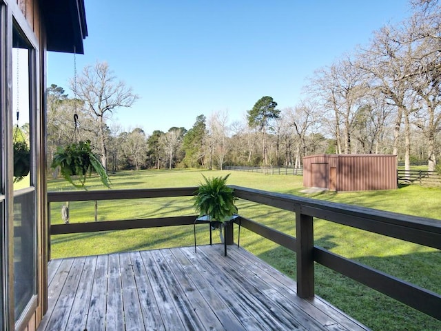 wooden deck featuring an outbuilding, a lawn, and fence