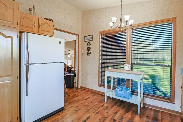 kitchen with light brown cabinetry, wallpapered walls, freestanding refrigerator, and wood finished floors