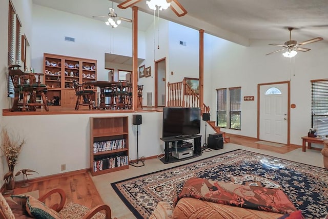 living area with visible vents, high vaulted ceiling, and stairs