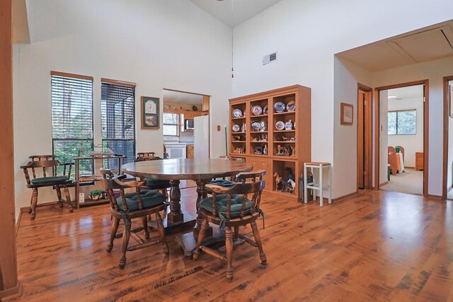 dining room with visible vents, a high ceiling, and wood finished floors