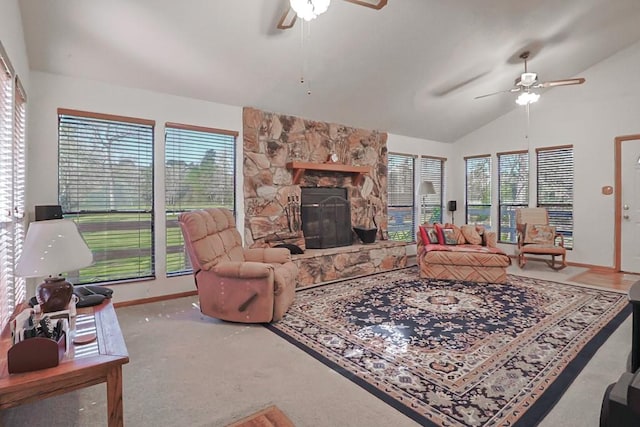 carpeted living room with a stone fireplace, lofted ceiling, baseboards, and ceiling fan