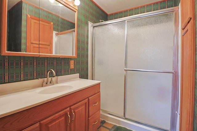 full bath featuring a stall shower, vanity, and wallpapered walls