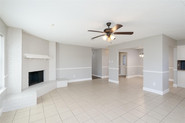 unfurnished living room featuring light tile patterned floors, a brick fireplace, baseboards, and ceiling fan