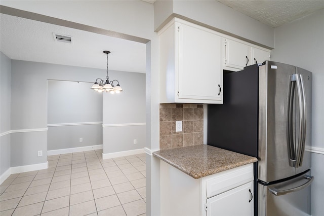 kitchen with visible vents, tasteful backsplash, freestanding refrigerator, white cabinets, and light tile patterned flooring