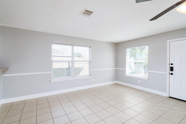 unfurnished room with visible vents, a textured ceiling, a ceiling fan, and baseboards