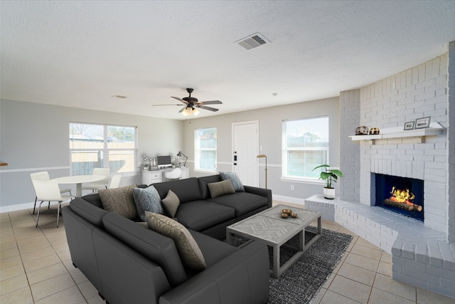 living room featuring a wealth of natural light, visible vents, a textured ceiling, and a fireplace