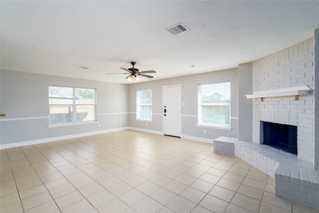 unfurnished living room with a ceiling fan, visible vents, baseboards, light tile patterned flooring, and a fireplace