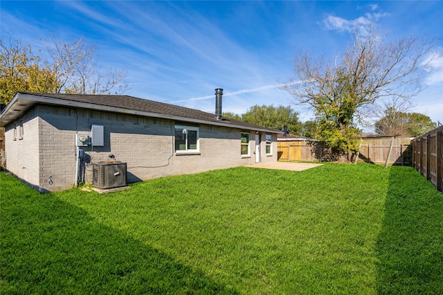 rear view of property with brick siding, a lawn, cooling unit, and a fenced backyard