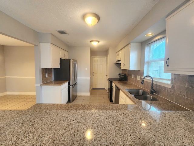 kitchen with light tile patterned floors, visible vents, freestanding refrigerator, a sink, and black range with electric cooktop