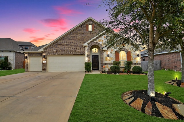 view of front facade featuring a lawn, driveway, fence, an attached garage, and brick siding