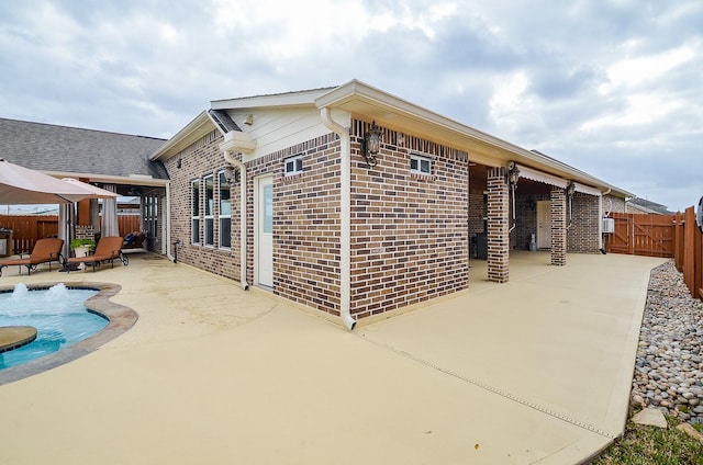 rear view of house with a gazebo, brick siding, a fenced backyard, and a patio area