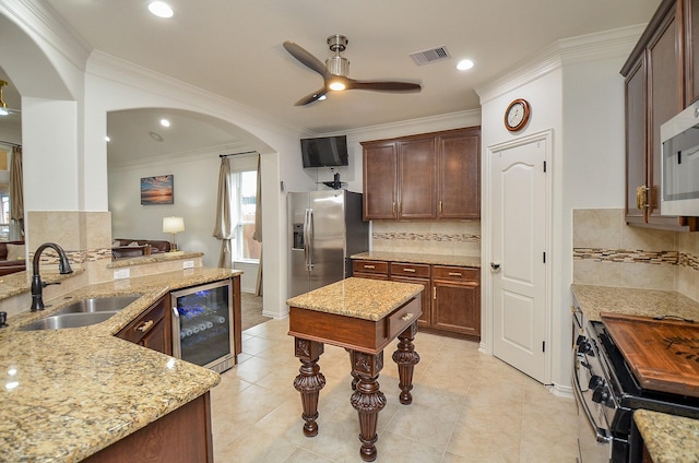 kitchen with visible vents, wine cooler, appliances with stainless steel finishes, arched walkways, and a sink