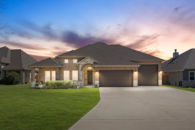 view of front of property with a front lawn, driveway, a shingled roof, a garage, and brick siding