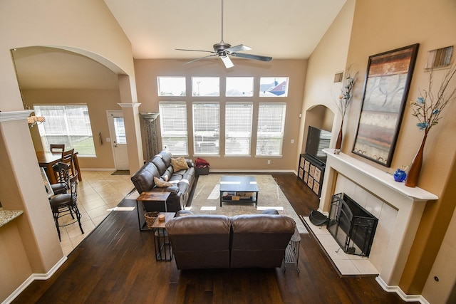 living room featuring arched walkways, a ceiling fan, hardwood / wood-style floors, and high vaulted ceiling