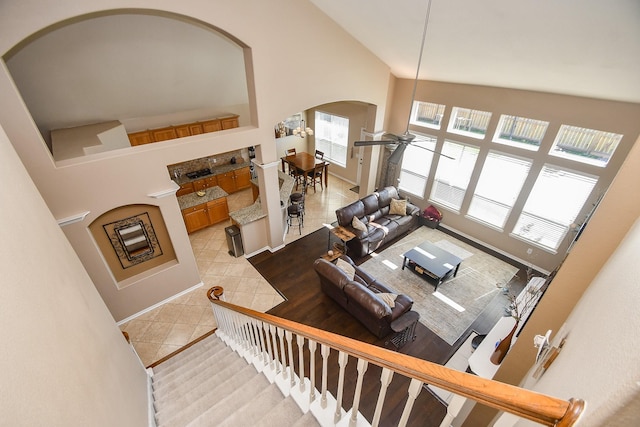 living area featuring light tile patterned floors, baseboards, arched walkways, and high vaulted ceiling