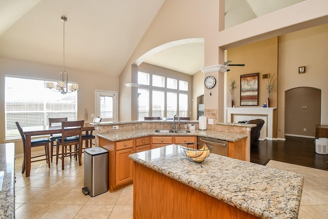 kitchen featuring high vaulted ceiling, a sink, light stone counters, a kitchen island, and dishwasher