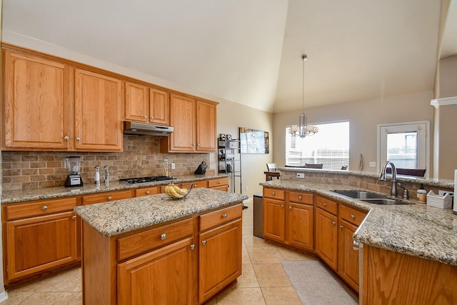 kitchen featuring a kitchen island, under cabinet range hood, decorative backsplash, gas stovetop, and a sink