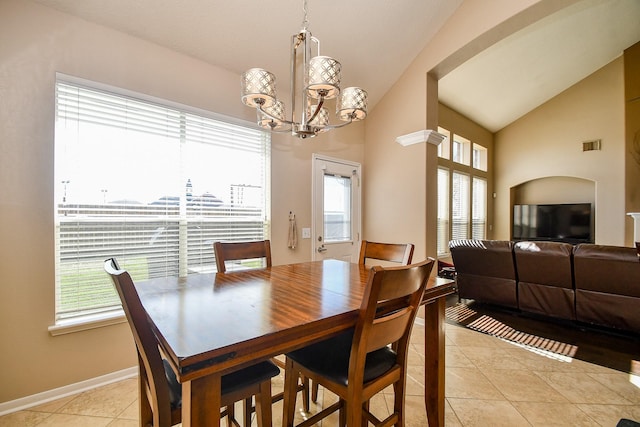 dining room with light tile patterned flooring, a healthy amount of sunlight, an inviting chandelier, and lofted ceiling