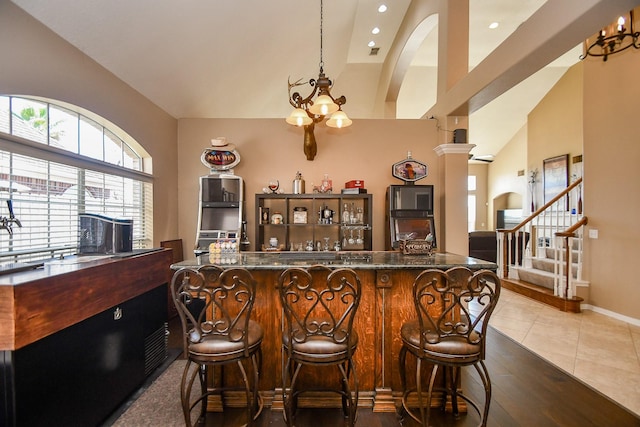 bar with stairway, arched walkways, a notable chandelier, and vaulted ceiling