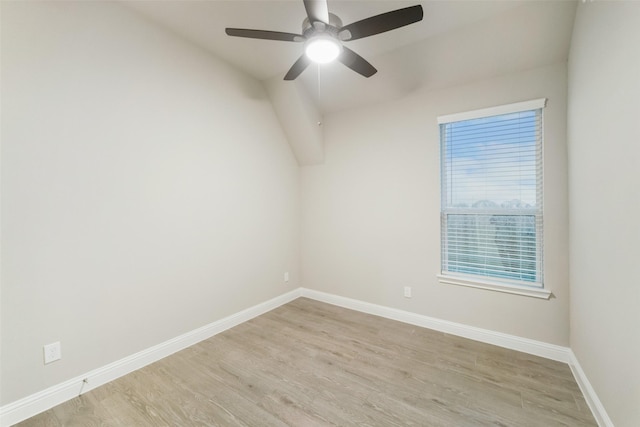 spare room with vaulted ceiling, light wood-style flooring, baseboards, and ceiling fan