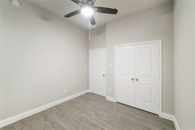 unfurnished bedroom with ceiling fan, baseboards, light wood finished floors, and a closet