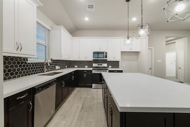 kitchen featuring a sink, stainless steel appliances, white cabinetry, dark cabinets, and visible vents