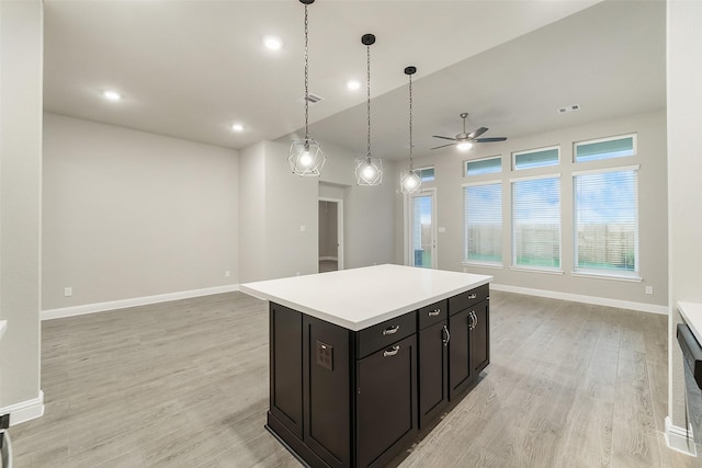 kitchen featuring light wood-type flooring, open floor plan, a ceiling fan, and a center island