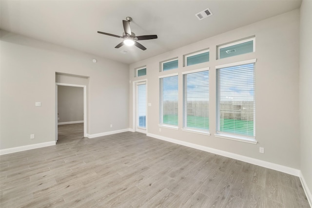 spare room featuring light wood-type flooring, visible vents, baseboards, and ceiling fan