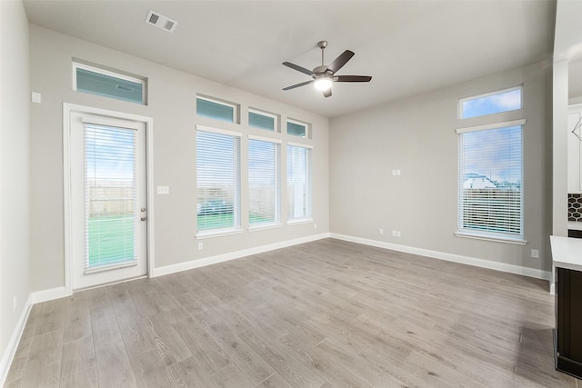 unfurnished room featuring light wood-type flooring, visible vents, baseboards, and a ceiling fan