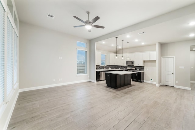 kitchen featuring backsplash, light wood finished floors, open floor plan, and stainless steel appliances