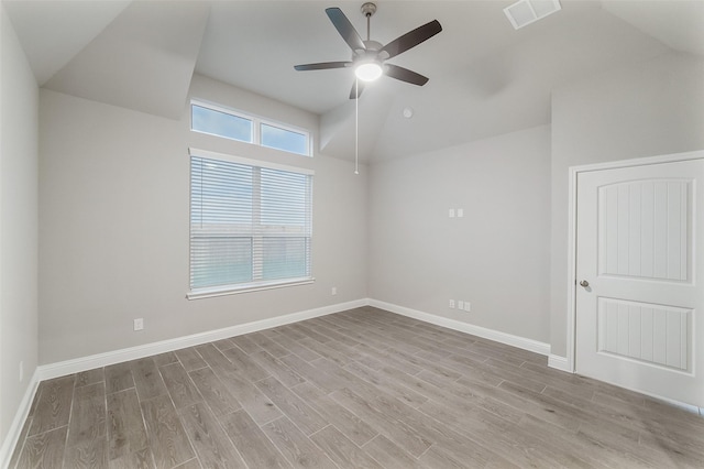 empty room with vaulted ceiling, wood finished floors, visible vents, baseboards, and ceiling fan