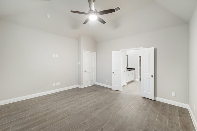 unfurnished bedroom featuring visible vents, baseboards, wood finished floors, and vaulted ceiling