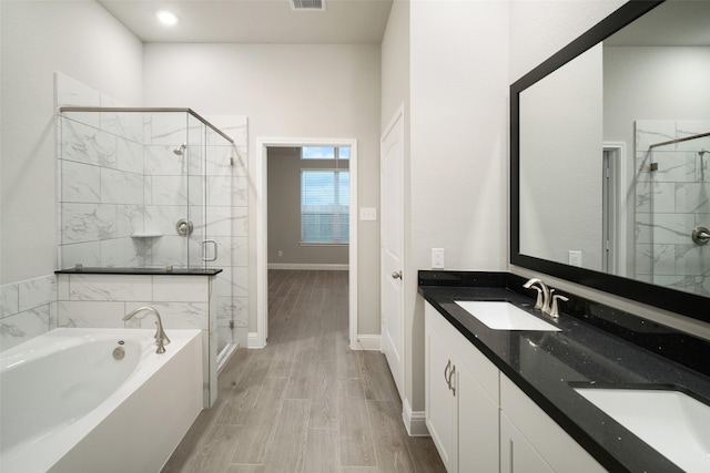 full bath with wood finish floors, a shower stall, a garden tub, and a sink