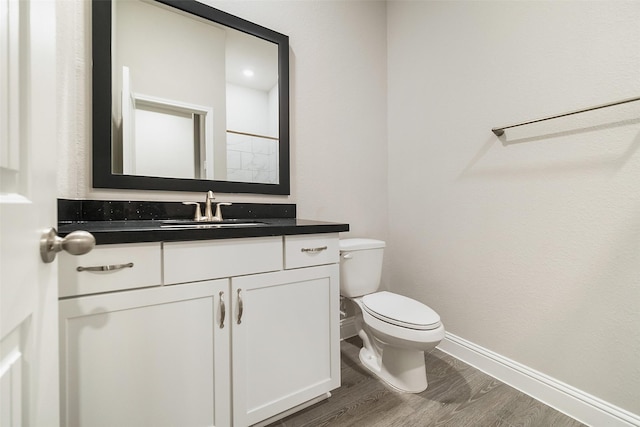 bathroom featuring vanity, toilet, wood finished floors, and baseboards