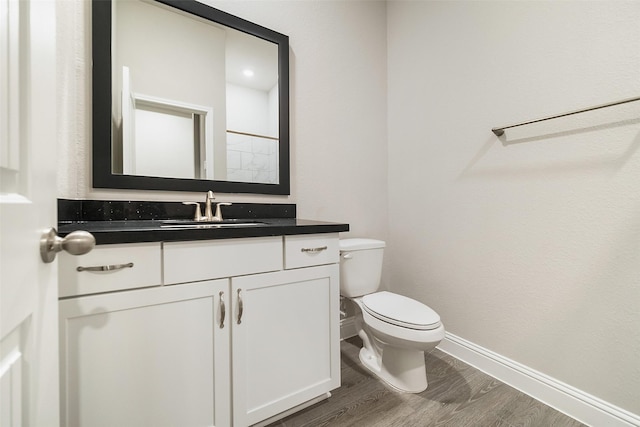 bathroom with baseboards, toilet, vanity, and wood finished floors