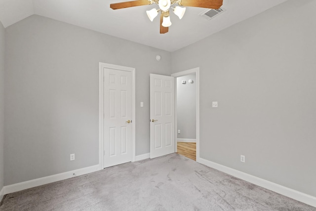 unfurnished bedroom with a ceiling fan, carpet, visible vents, baseboards, and lofted ceiling