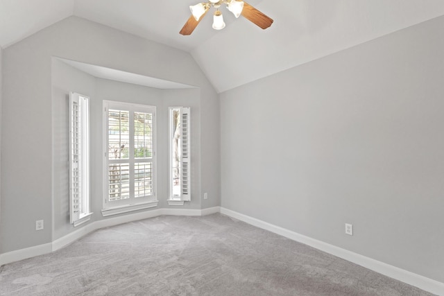 spare room with lofted ceiling, carpet flooring, a ceiling fan, and baseboards