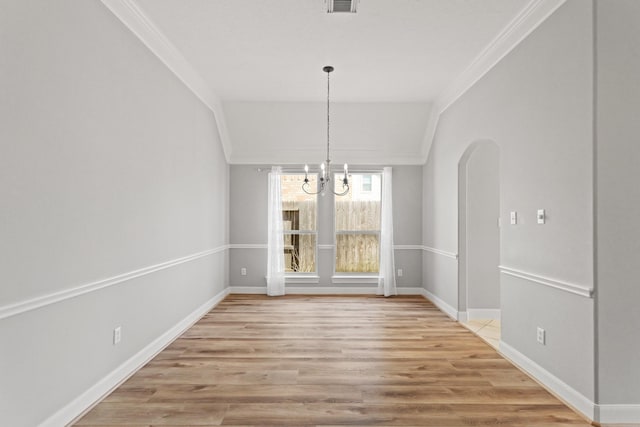 unfurnished dining area with a notable chandelier, arched walkways, light wood-style floors, and crown molding