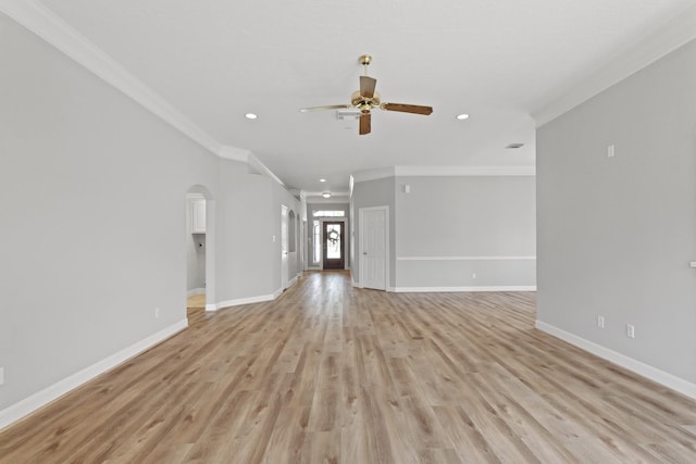 unfurnished living room with light wood-style flooring, arched walkways, baseboards, and ornamental molding