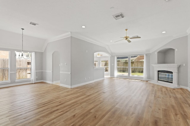 unfurnished living room with lofted ceiling, ceiling fan with notable chandelier, visible vents, and a high end fireplace